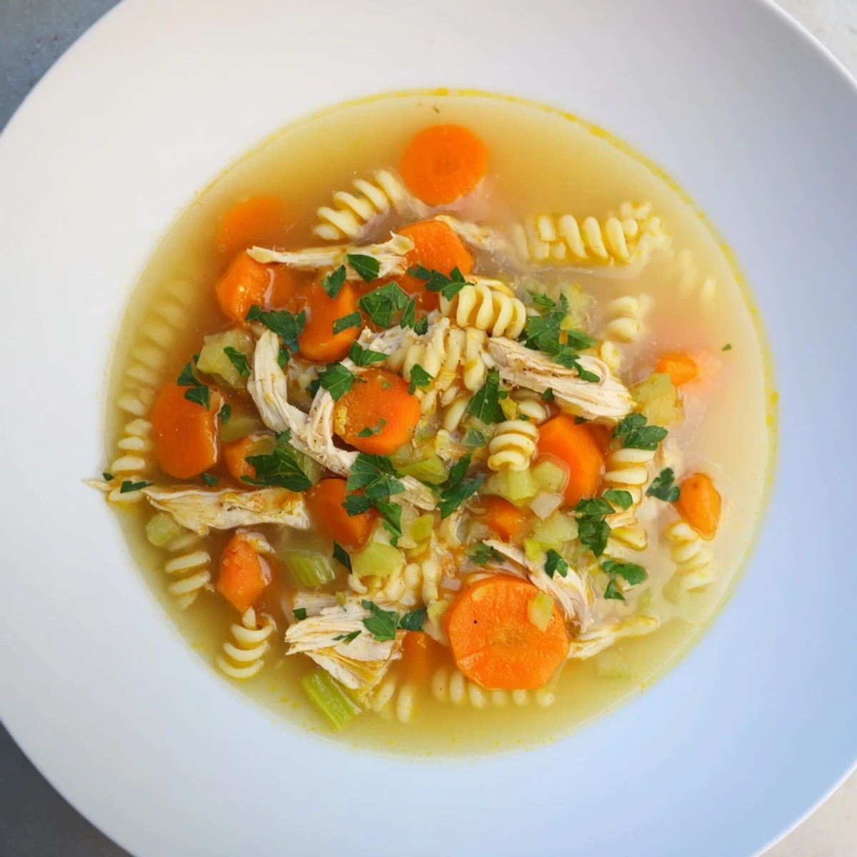 Steaming bowl of Chicken and Ditalini Flu Fighter Soup, garnished with fresh parsley, ready to serve.