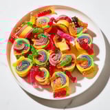 Bright fruit roll-up Rainbow Candy Roll Ups, filled with colorful gummy candies, await slicing for a fun party treat.