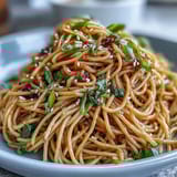 Aromatic ginger-scallion noodles tossed with vibrant sautéed greens in a savory Asian-inspired sauce.