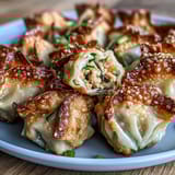 Crispy pan-fried chicken and veggie dumpling bites wrapped in rice paper, served with a savory dipping sauce.  