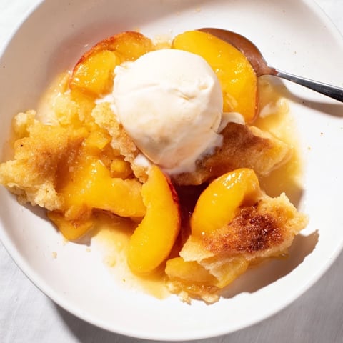 Buttery Peach Cobbler served warm with melting vanilla ice cream on top.  