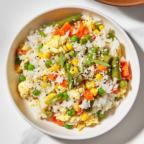 Steaming frozen veggie fried rice with visible fluffy egg pieces, seasoned perfectly with soy sauce.