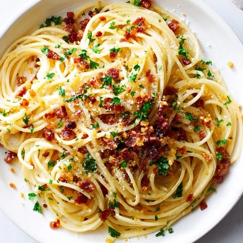A plate of Garlic Butter Pasta with Crispy Bacon with golden, crunchy bacon topping.