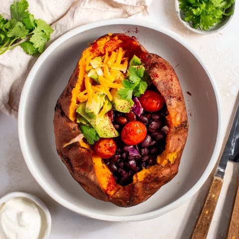 Golden-brown Loaded Baked Sweet Potatoes, brimming with flavorful black beans and fresh green toppings.