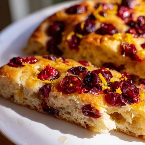 Golden-brown Cranberry Orange No-Knead Focaccia topped with bright cranberries and orange zest, ready to serve.