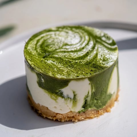 Creamy matcha swirl cheesecake cups, with a crisp cookie base, and topped with whipped cream.