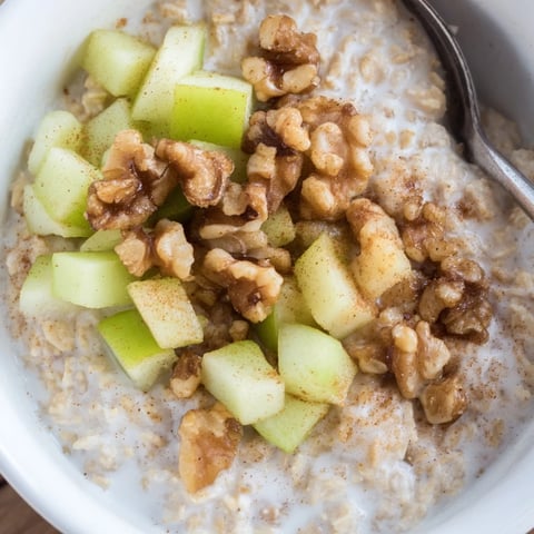 Warm and comforting apple pie oatmeal bowl topped with sweet, caramelized apples and crunchy walnuts.