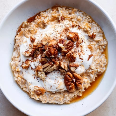 Steaming bowl of Pumpkin Spice Latte Oats, topped with whipped cream and chopped pecans.