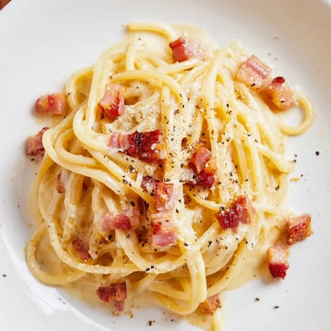 Express Spaghetti Carbonara: Creamy pasta coated in a rich egg sauce, sprinkled with Parmesan and pepper.