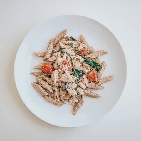 Golden brown chicken pieces and al dente penne tossed in a creamy Greek Yogurt Chicken Pasta sauce, with wilted spinach and halved cherry tomatoes.
