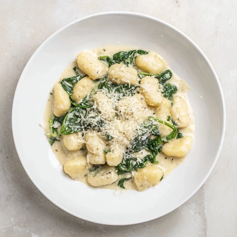 Creamy Garlic Gnocchi twirls in a rich garlic Parmesan sauce, with wilted spinach leaves clinging to each pillowy potato dumpling.