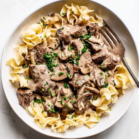 Savory easy beef stroganoff garnished with fresh parsley on a white plate.  