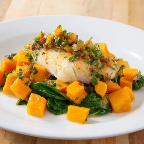 Golden baked Cod accompanied by roasted butternut squash in a flavorful tomato-herb sauce.
