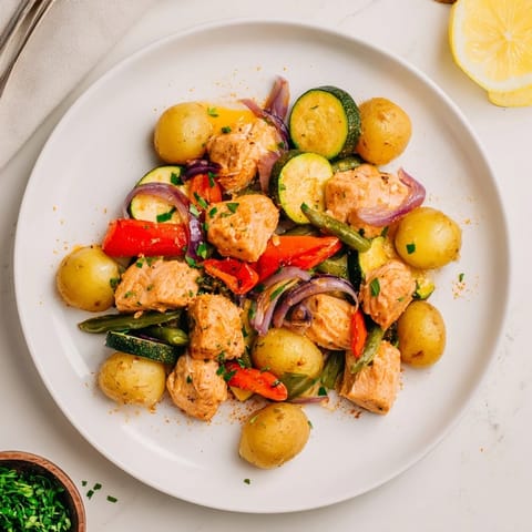 A close-up of a sizzling Salmon & Potato Skillet, showcasing flaky salmon and crispy potatoes.