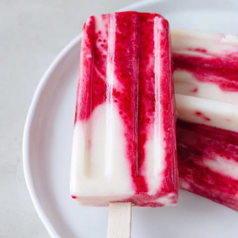 Frozen Raspberry Coconut Ice Pops, layered with red and white, are a perfect summertime dessert favorite.
