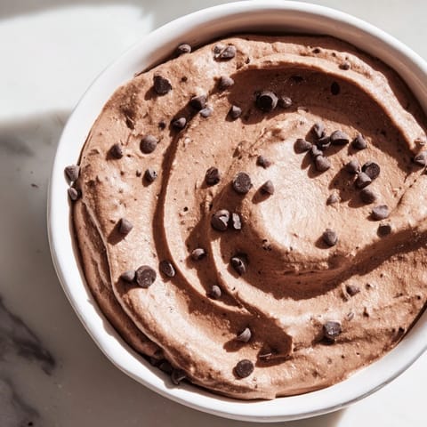 This decadent chocolate hummus features a swirl of chocolate chips, perfect for a quick vegan snack.