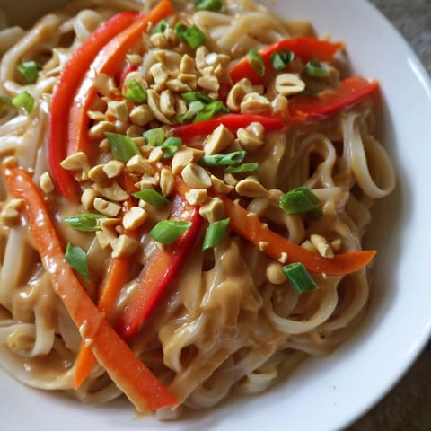Close-up of freshly made Spicy Peanut Noodles, the creamy sauce coating every perfectly cooked noodle.
