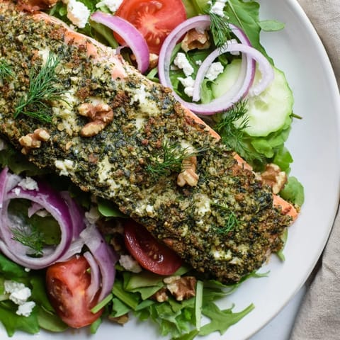 Warm and flaky herb-crusted salmon salad, served with fresh cherry tomatoes and cucumber.
