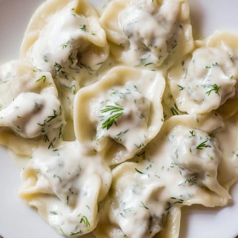 Close-up of golden-brown Russian pelmeni, perfectly cooked and served with creamy sour cream sauce.