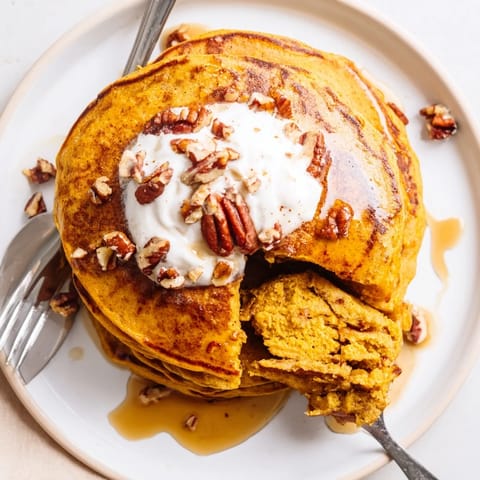 Golden-brown Pumpkin Spice Pancakes stacked high, drizzled with warm maple syrup and dusted with powdered sugar for a cozy autumn breakfast.