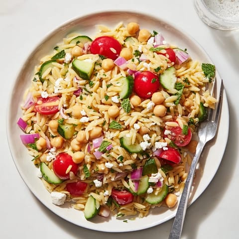 Bright Mediterranean flavors shine in this Lemony Chickpea Orzo Salad, featuring feta crumbles and a zesty lemon vinaigrette.