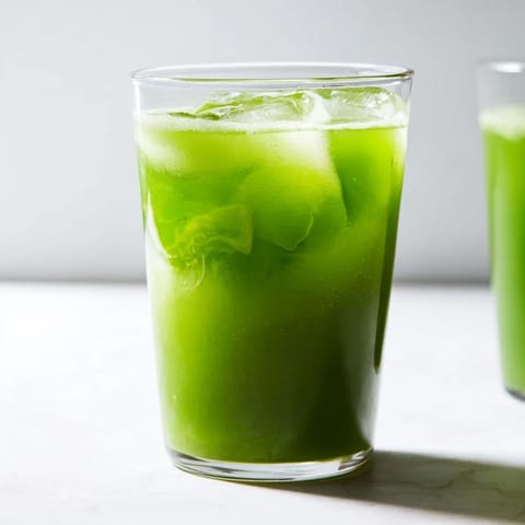 Bright green detox juice with cabbage, kale, lemon, and ginger in a chilled glass.  