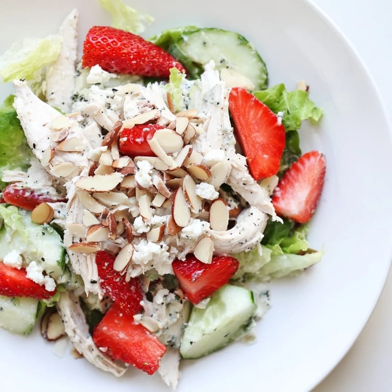 Vibrant Strawberry Poppy Seed Chicken Salad featuring juicy strawberries, cool cucumbers, and shredded chicken tossed in a creamy poppy seed dressing on a bed of greens.